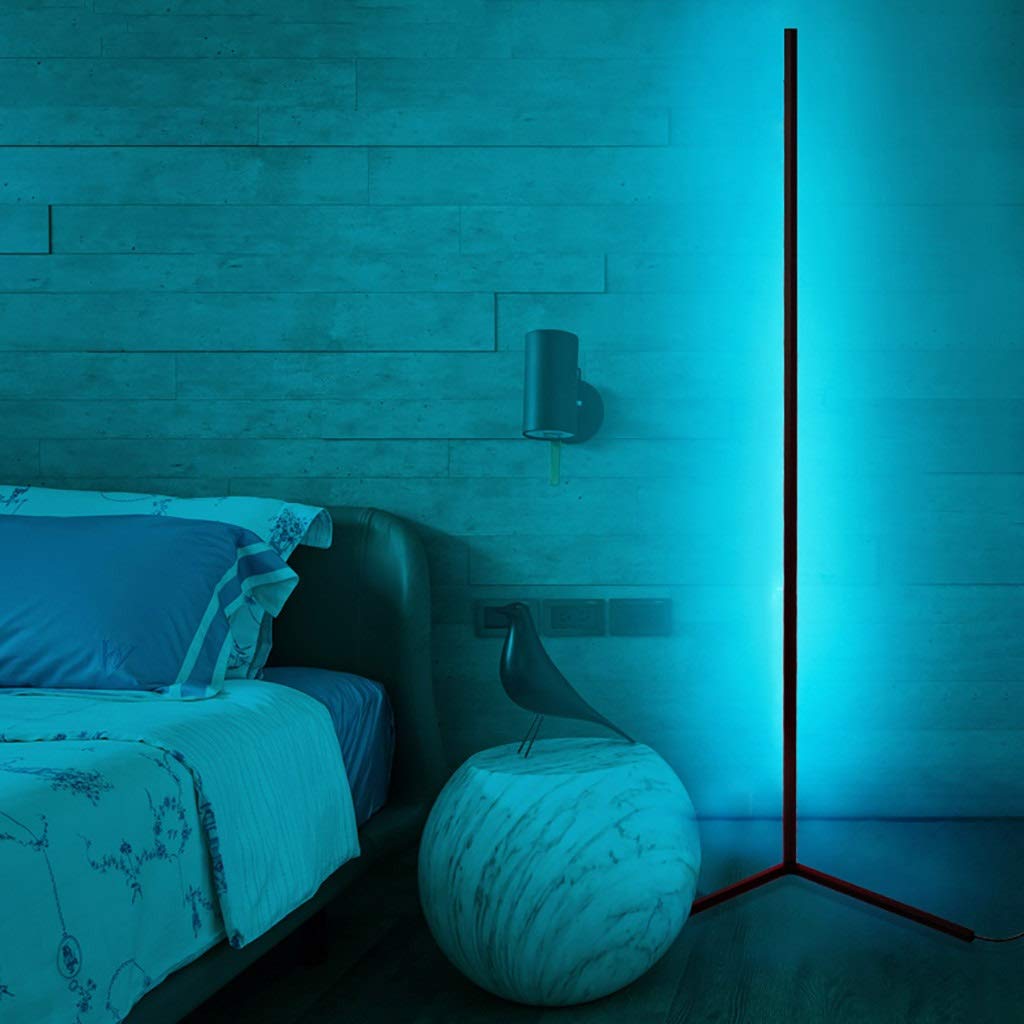 A bright bedroom lit up turquoise by an Enlights LED vertical strip lamp on a black V stand in the corner of the room. 